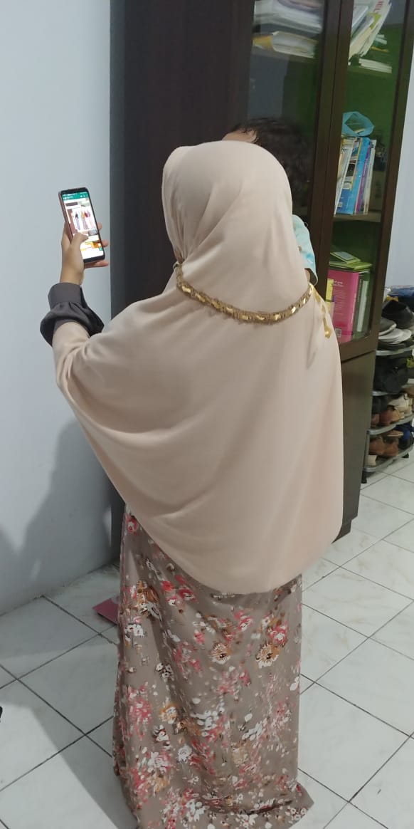 Eine SMBOS-Resellerin interagiert mit ihrem Kunden, während sie sich um ihren Sohn kümmert © Fathimah Fildzah Izzati