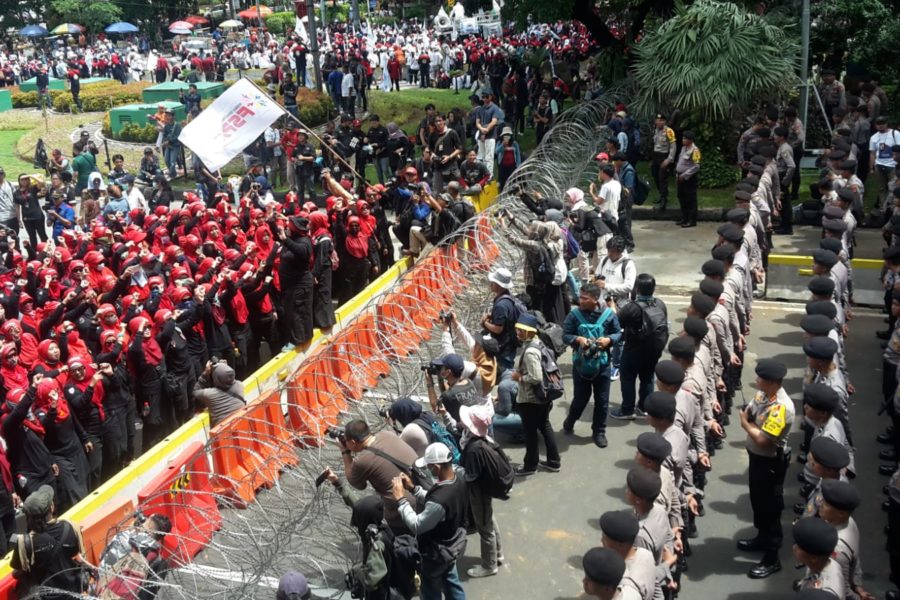 Arbeiter*innen der Föderation Verschiedener Industriezweige (FSPASI), eine Abspaltung von dem in der Suharto-Ära gegründete Staatsgewerkschaft SPSI, marschieren zum Palast des Präsidenten in Jakarta. Ihr Weg wird durch Stacheldraht und Polizisten blockiert © Marulloh, 2019